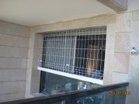 התקנה של סורגית על חלון הסלון. מכיוון שהחלון מורכב בחלקו התחתון מזכוכית קבועה שאינה נפתחת הסורגית הותקנה על החלק שנפתח בלבד